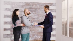 Real estate agent in business suit giving keys to young couple